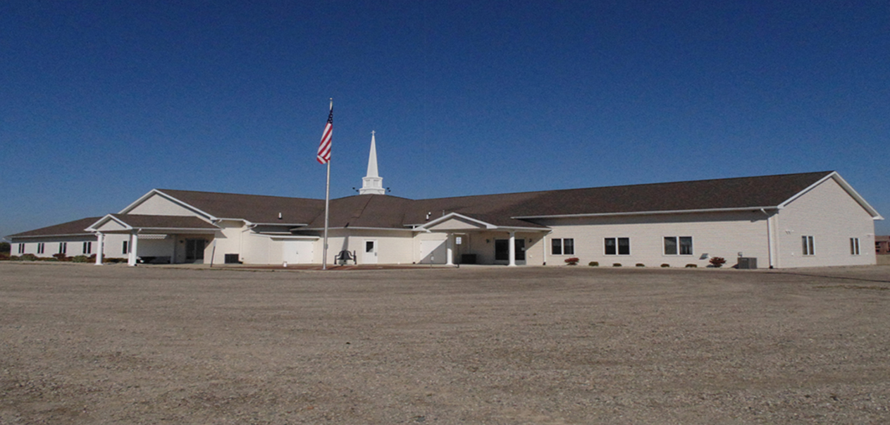 White church with steeple and American flag outside.