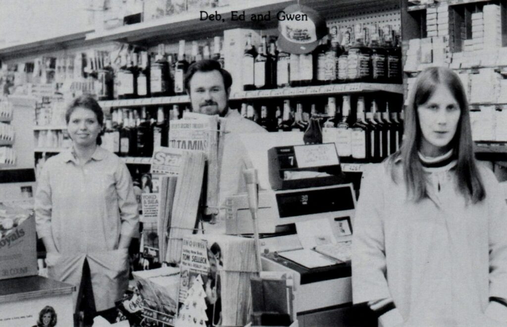Three people working in a store, standing by registers.