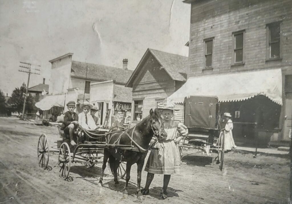Vintage street scene with horse-drawn carriage, people standing.
