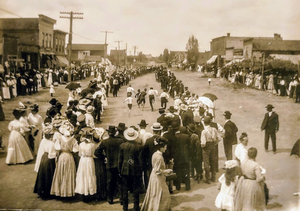 Historic street race with spectators in early 1900s attire.