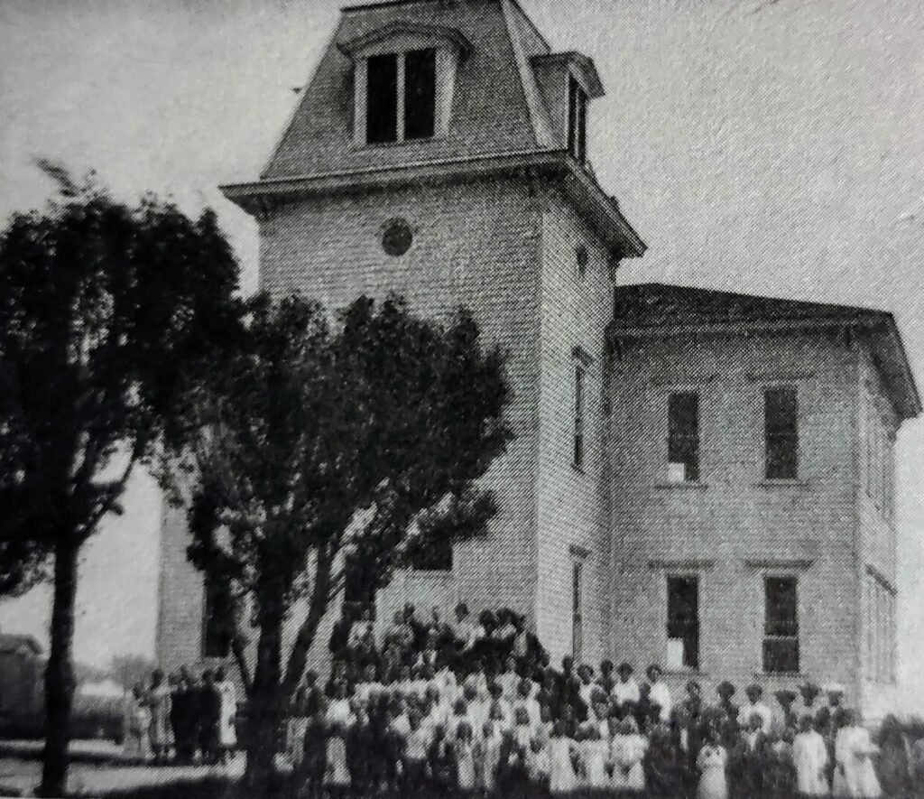 Old school building with large group outside