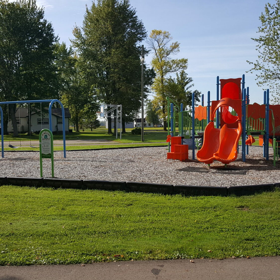 Playground with swings and slides in a park setting.
